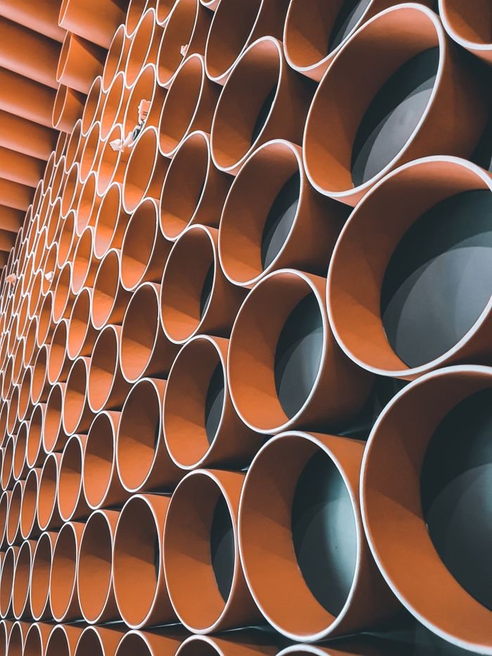 Abstract view of stacked orange industrial pipes creating a geometric pattern.